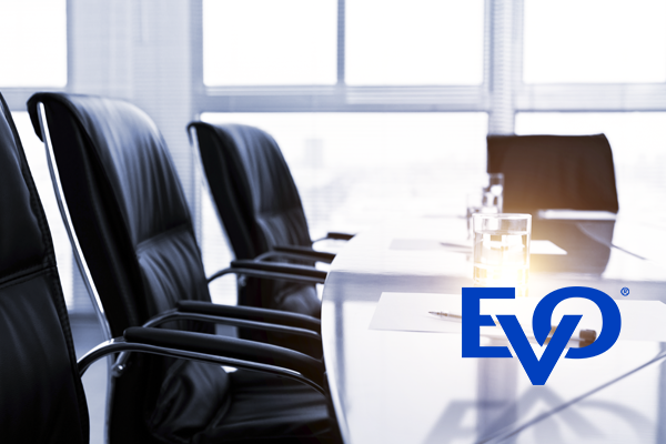 An empty board room table with the EVO logo